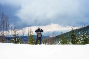 beautiful-shot-man-taking-picture-snowy-forested-mountains-scaled